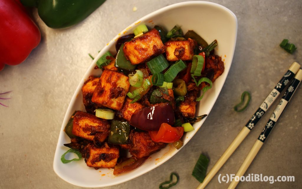 Dry Chilli Paneer garnished with Spring Onions with Chopsticks